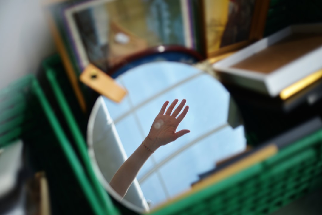 Home a-hand-reflected-in-a-round-mirror-surrounded-by-objects-fuzarkl6heg